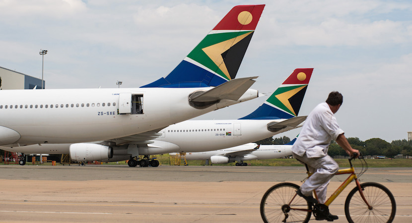 A man cycles past Airbus Group NV A340, left, and A330-200 aircraft operated by South African Airways at O.R. Tambo International airport in Johannesburg, South Africa. Photographer: Waldo Swiegers/Bloomberg